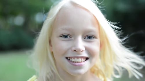 Little Happy Cute Girl Looks To Camera in the Park - Windy Blows Her Hair