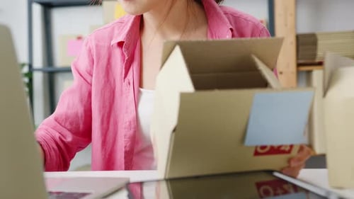 Young Asian woman check product purchase order on stock and save to computer laptop work at home.