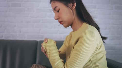 Young Woman Massaging Sore Hand Indoors