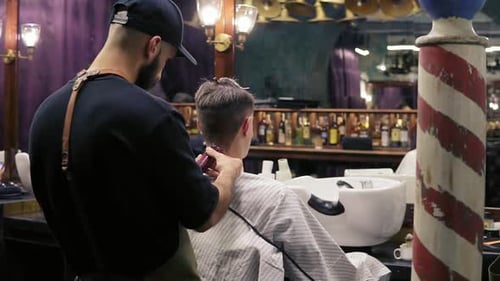 Rückansicht eines jungen Friseurs, der mit einem elektrischen Trimmer Haare am Hals seines Kunden schneidet