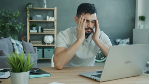 Frustrated Man Working At Laptop In Home Office