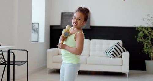 Enthusiastic Girl Singing and Dancing with Toy Microphone