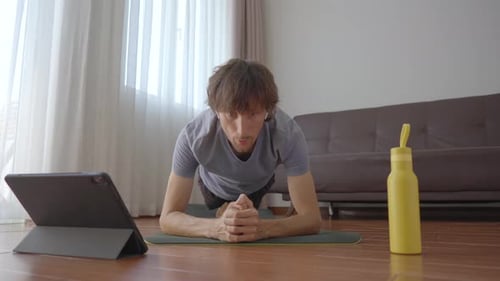 Man Doing Plank Exercise with Tablet in Living Room