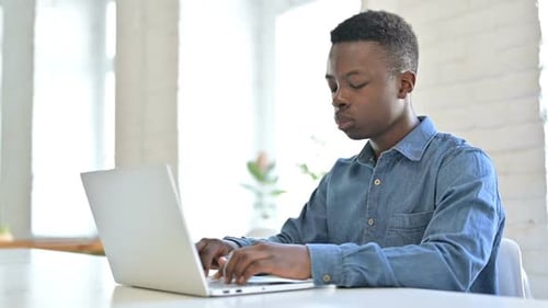 Young African Man Working on Laptop in Office