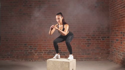 Beautiful Female Bodybuilder Performing Squats Jumping on Fit Box in Gym