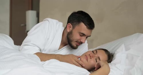 Un homme embrasse sa petite amie pour se réveiller dans un grand lit confortable
