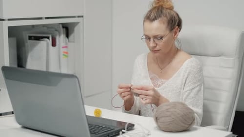 The Mature Woman Knitting in the Office. Woman Knitting and Sitting in the Office While Having a