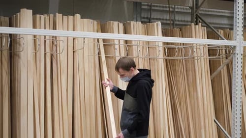 Carpenter Selecting Lengths of Cut Wood in Store