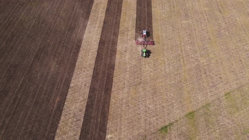 Tractor plowing rural field during daytime, aerial view