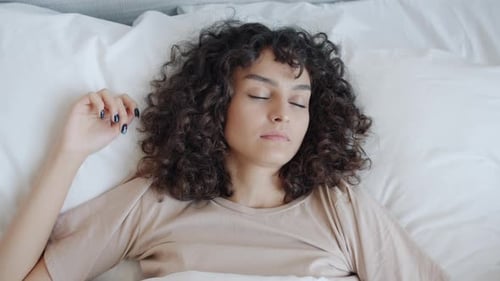 Top View of Cute Curlyhaired Girl Sleeping in Comfortable Bed Lying Alone with Eyes Closed