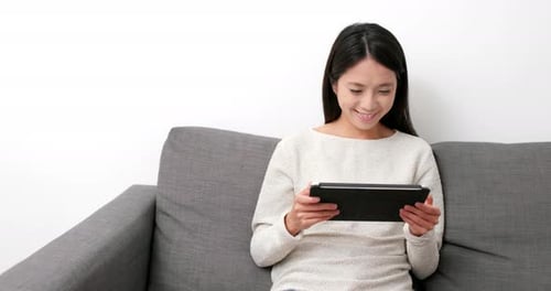 Woman Relaxing at Home Using Tablet Device