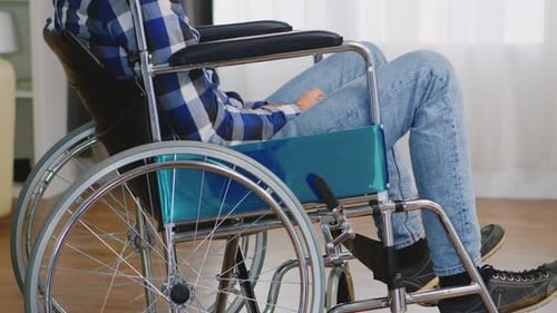 Man Sits Quietly in Wheelchair by Window