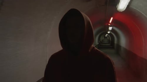 Junge im Kapuzenpullover läuft im dunklen Tunnel