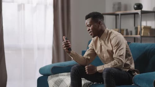 Man Video Chats on Smartphone from Couch
