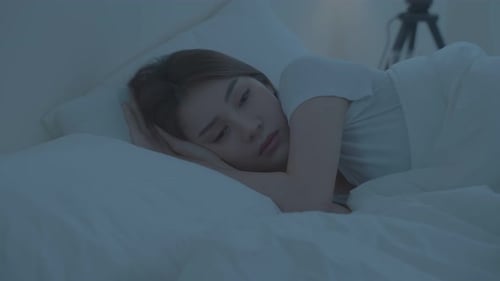 Asian beautiful insomnia woman lying down on bed in bedroom thinking about life problem at night.