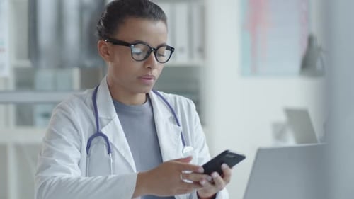 Female Doctor Using Smartphone at Workplace in Medical Office
