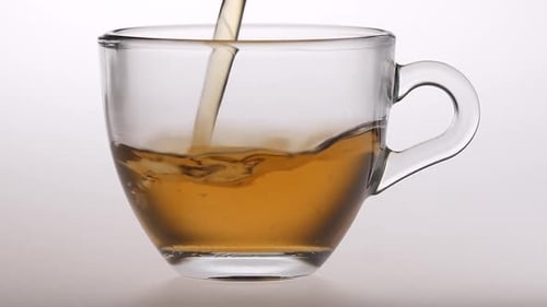 Pouring Tea into a Glass Mug Close Up