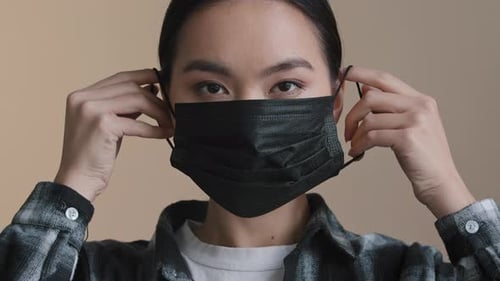 Young Adult Putting on Black Medical Mask