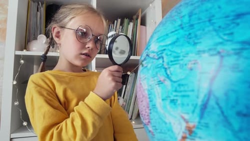 Young Girl Studying Globe With Magnifying Glass