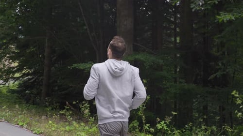 Athlete man is jogging in the forest.