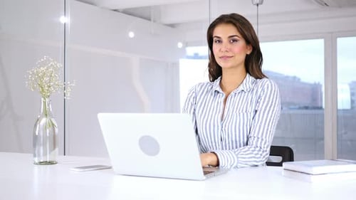 Woman Typing on Laptop in Modern Office Smiling