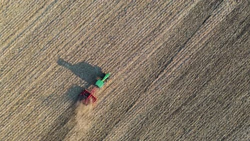 Tractor Plowing Dry Farm Field from Above