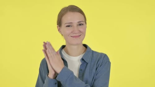 Smiling Woman Clapping on Yellow Background