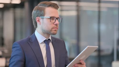 Frustrated Young Adult Man Using Tablet in Office