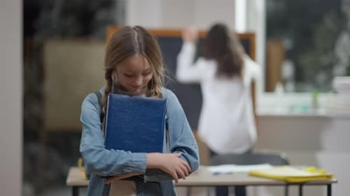 Smiling Student Holding Book in Classroom