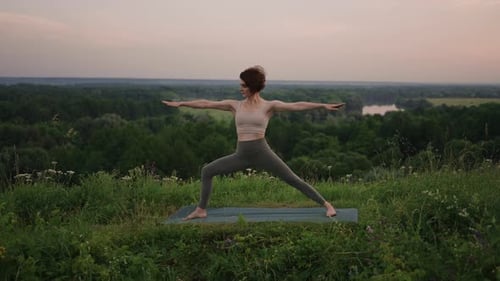 Woman Practices Yoga on Hill at Sunset