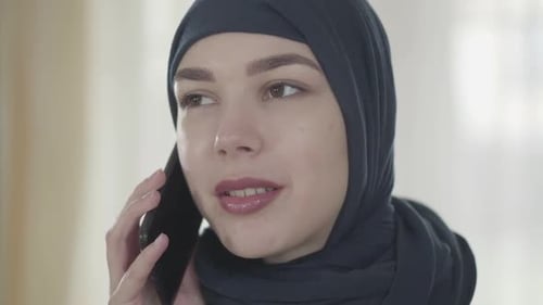 Portrait of a Young Beautiful Muslim Woman in Black Headdress Talking By Cell Phone