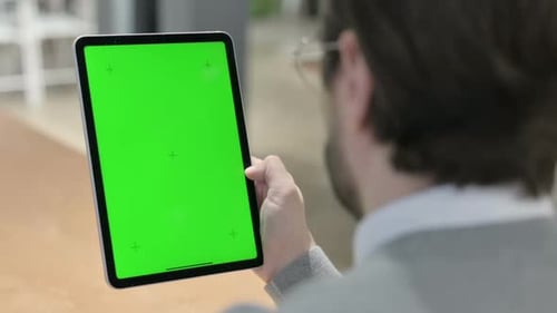 Man Looking at Tablet with Green Chroma Screen
