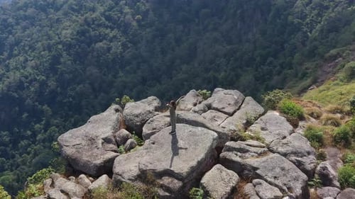 Drone view Young hiking woman standing on rocky peak