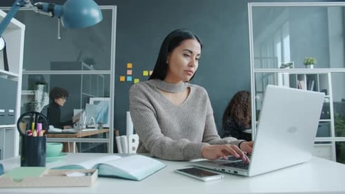 Stressed Woman Working on Laptop in Modern Office