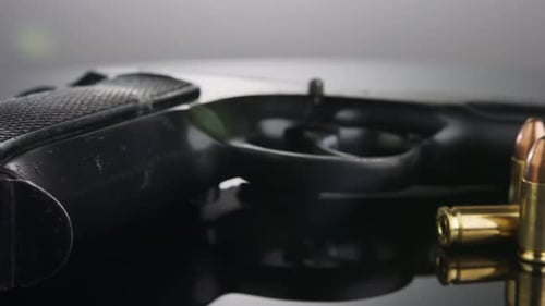 Gun Control. 9-mm-Handfeuerwaffe mit Kugeln, die sich auf einer reflektierenden Oberfläche drehen