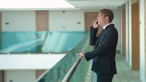 Man in Suit Talking on Phone in Hallway