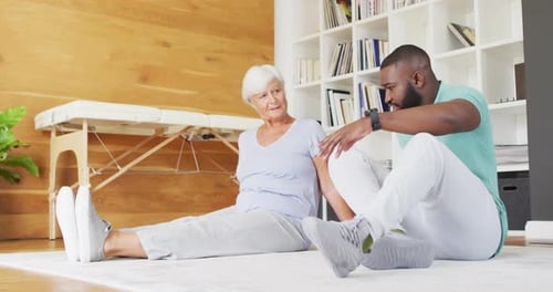 Man Assists Senior Woman Stretching in Home