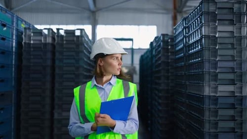 Female Storage Employee Inspecting Blue Delivery Boxes Managing Factory Shipment