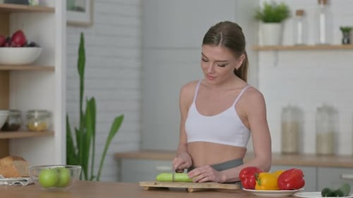 Young Adult Woman Slicing Cucumber in Bright Kitchen