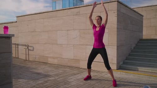 Young Woman Exercising Outdoors Doing Jumping Jacks