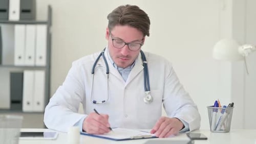 Doctor Writes Notes at Desk in Office