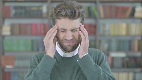 Stressed Young Adult with Headache in Library