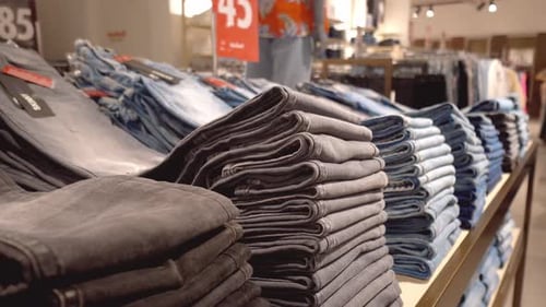 Jeans or denim pants are neatly folded on shelf or window in clothing store.