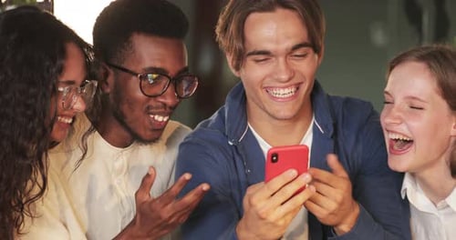 Crop View of Joyful Friends Looking at Mobilephone Screen and Laughing. Group of Young Smiling