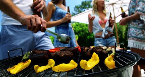 Group of friends having a bottle of beer while preparing barbeque