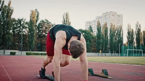Muscular Man Prepares on Track for Running Sprint