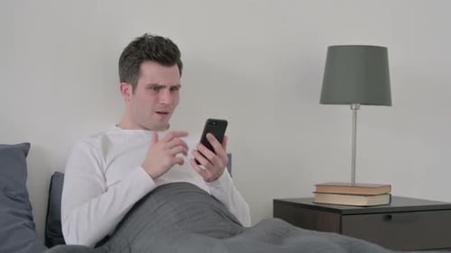 Shocked Man in Bed Reacts to Phone