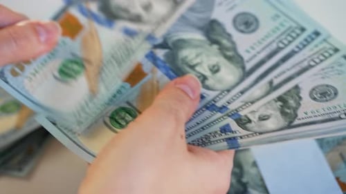 Hands Counting US Dollar Bills or Paying in Cash