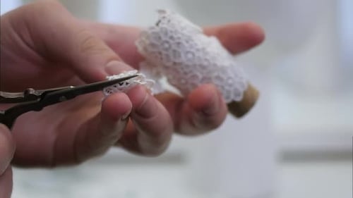 Female Hand Cuts White Fabric with Scissors