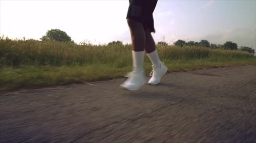 Strong Man in Shorts and Sneakers Running Among Green Field
